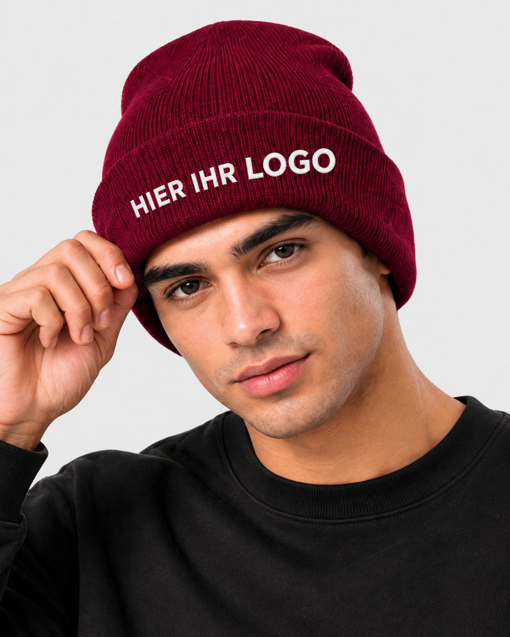 Mann mit bordeauxroter Strickmütze, Logo vorne am Umschlag gestickt